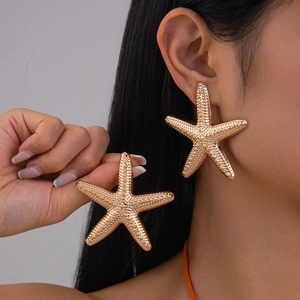 Detail view of large gold starfish earrings showing realistic texture and metallic shine