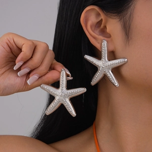 Detailed close-up of silver starfish earrings with textured surface worn by a model
