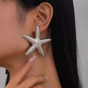 Close-up of oversized silver starfish earrings with realistic textured metal finish