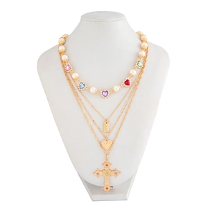 Detail van gelaagde kruisketting met parels en kleurrijke hartvormige stenen