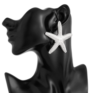 Detail of a large silver starfish earring with textured bead finish on a model's ear