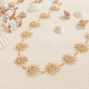 Détail des maillons de chaîne de corps soleil doré en métal sur un fond de sable d'été