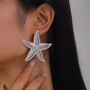 Macro shot of silver starfish earring with detailed textured surface on a model's ear