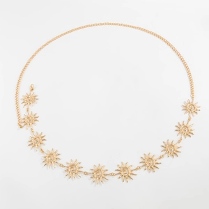 Détail d'une chaîne de taille dorée avec pendentifs soleil, texture spirale et fermoir mousqueton