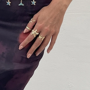 Close-up of ocean-themed gold ring set with starfish and whale tail designs