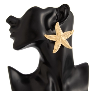 Detailed view of large gold starfish earrings featuring a realistic textured metal surface