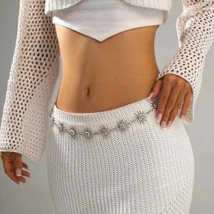 Détails de breloques soleil argentées sur une chaîne de taille en métal sur tricot blanc