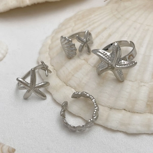 Detail of silver starfish and seashell adjustable rings set on a decorative white shell