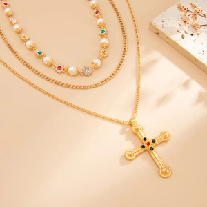 Detail van de gelaagde gouden ketting met parels en vintage kruisvormige hanger