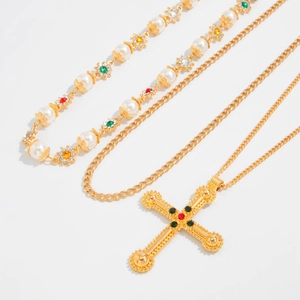 Close-up van een vintage gouden ketting set met kruishanger en parelmoeren bloemdetails