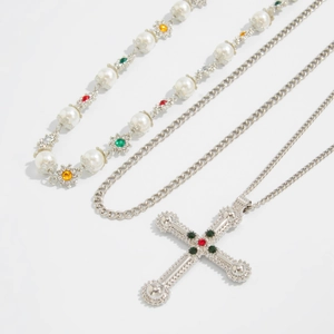 Detail van kruishanger en gelaagde parelketting met kleurrijke edelstenen en zilveren ketting