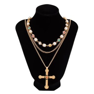 Detail van kruis hanger ketting met kleurrijke edelstenen en gelaagde parels