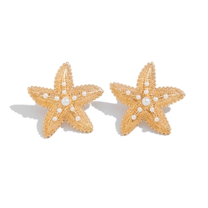 Detailed macro shot of golden starfish earrings with inlaid white pearls on white background