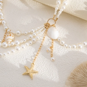 Détail de chaîne de corps en perles multicouche avec étoile de mer et pendentifs coquillages