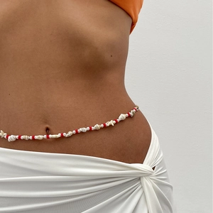 Détail de chaîne de taille de plage avec coquillages, perles rouges et perles