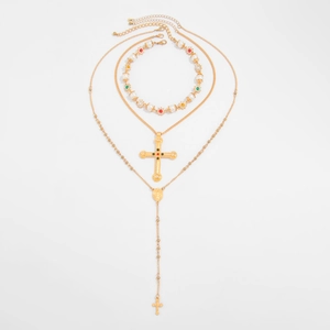 Detailweergave van gelaagde gouden kettingen met kruishangers, parels en religieuze penningen