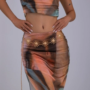 Détail d'une chaîne de taille dorée bohème avec motifs soleil en relief sur mannequin