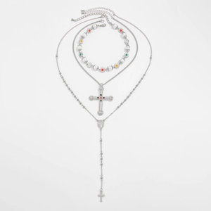 Detailopname van de drielaagse zilveren kruisketting met parels en edelstenen