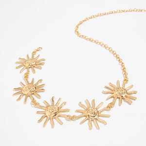 Détail de la chaîne de taille dorée avec des pendentifs soleil souriants en métal brillant