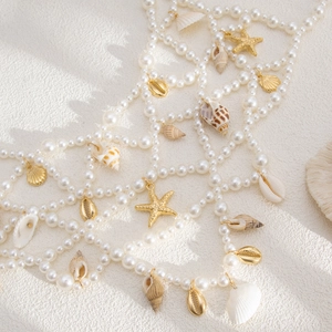 Détail de chaîne de corps en perles avec pendentifs étoiles de mer et coquillages