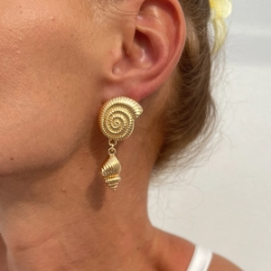 Macro shot of gold conch shell drop earrings showing spiral texture and vintage metal finish
