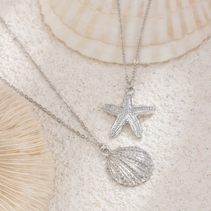 Silver body chain with starfish and shell pendants on sand for beach vacation