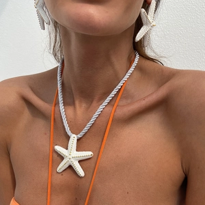 Vista de cerca del collar y pendientes de estrella de mar blanca con textura dorada