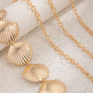 Macro detail of golden metal shell pendants on a bohemian beach body chain