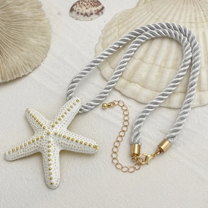 Detalle macro del colgante de estrella de mar en cadena trenzada con cierre de mosquetón dorado