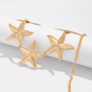 Detailed macro shot of three textured golden starfish pendants on a sleek metal body chain