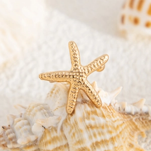 Macro shot of gold starfish earring with detailed texture on a natural seashell