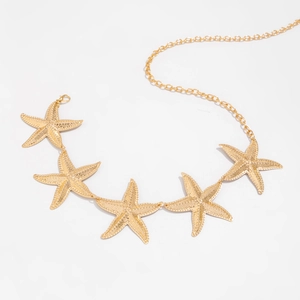 Macro shot of gold starfish charms with textured details on a bohemian body chain waist belt