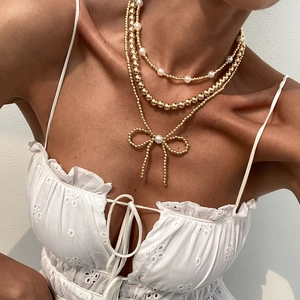 Bohemian multi-layer necklace with gold beads, faux pearls and a bowknot pendant