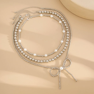 Detailed view of silver layered pearl necklace featuring a metallic bow pendant charm