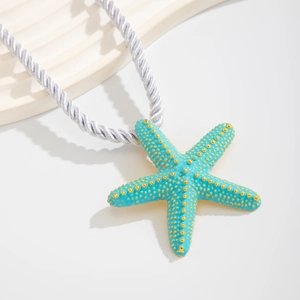 Detalle del colgante de estrella de mar azul con textura dorada en cordón trenzado lila