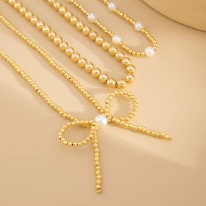 Bohemian gold beaded necklace set with faux pearl accents and a stylish bow pendant