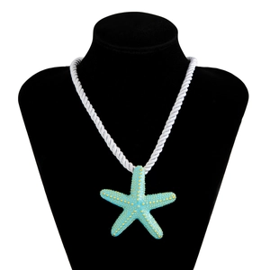 Detalle del colgante de estrella de mar azul con puntos dorados en collar de cuerda blanca