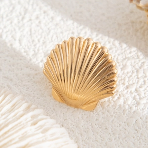 Macro detail of golden seashell earrings with a polished metallic ribbed texture