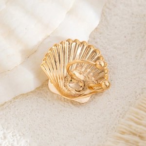 Macro detail of golden seashell ear cuff with radial texture on a white stone base