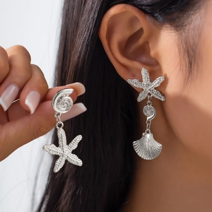 Detail of silver asymmetric earrings with starfish and seashell charms for beach vacations