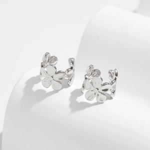 Detail of silver floral ear cuffs with polished metallic finish and open C-shape design