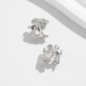 Macro shot of silver five-petal flower ear clips with high-polished metallic finish