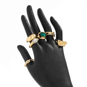 Detail van vergulde ringen met smaragdgroene edelsteen en heldere zirkonia-stenen
