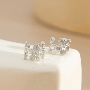 Detailed close-up of shiny silver starfish earrings on a white professional jewelry stand