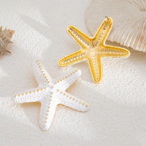 Detalle de los pendientes de estrella de mar con textura dorada y acabado blanco mate