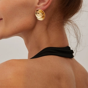 Detailed close-up of golden round stud earrings with textured spiral vintage design