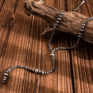 Detail of vintage Navajo style beaded necklace with antique silver finish on wood