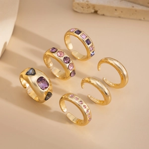 Six-piece gold-toned adjustable ring set with colorful gemstones on a minimalist display