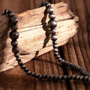 Detail of vintage Y-shaped beaded necklace with frosted metal finish on driftwood