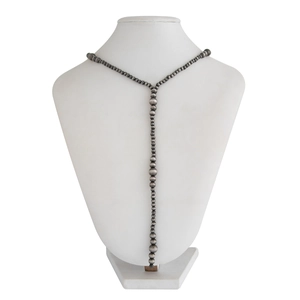 Macro shot of long Y-shaped necklace with brushed silver-finish beads on white bust
